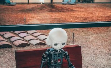 The Pros and Cons of AI in Education Explained Image of a AI robot using a laptop showing the pros of AI in education