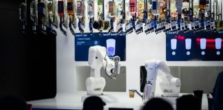 Business Process Automation vs Robotic Process Automation an image of business people looking at a robotic arm preparing drinks, which is to improve the business process automation cycle