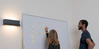 Best Capacity Planning Software in 2025 2 people discussing the Best Capacity Planning Software by using a white board and sticky notes